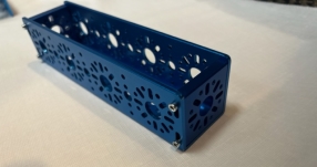 A blue rectangular object with holes

Description automatically generated