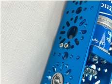 A blue metal object with holes and screws

Description automatically generated