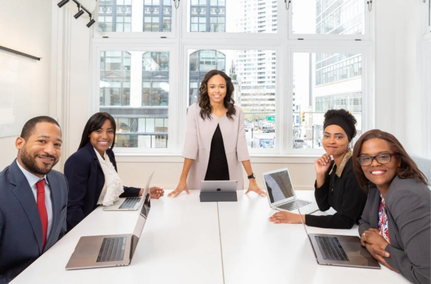 A group of people sitting around a table with laptops

Description automatically generated with medium confidence